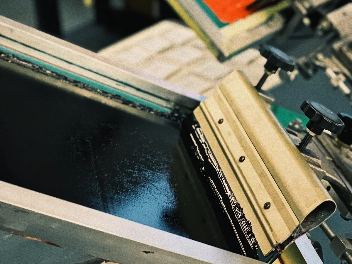 Screen printing press with orange and black ink in our workshop