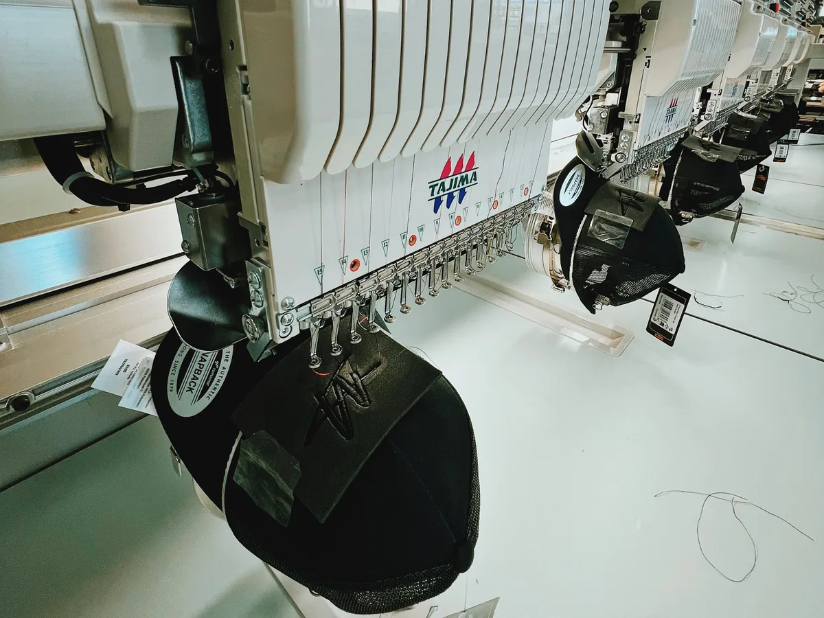 A Tajima embroidery machine stitching a logo onto a Flexfit cap in our workshop
